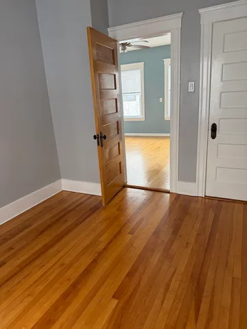 a view of empty room with wooden floor and fan