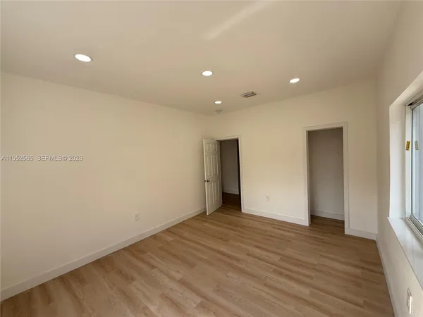 a view of an empty room with wooden floor and closet