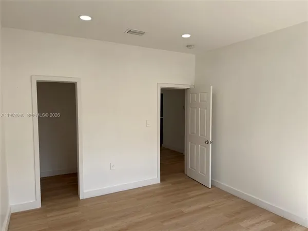 an empty room with wooden floor & closet area