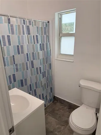 a white toilet sitting next to a sink a small mirror