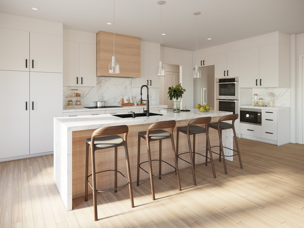 63 Green Street, Unit 2 Brookline, MA 02446 - Photo 5 of 12 a kitchen with stainless steel appliances kitchen island granite countertop a stove a refrigerator and white cabinets with wooden floor
