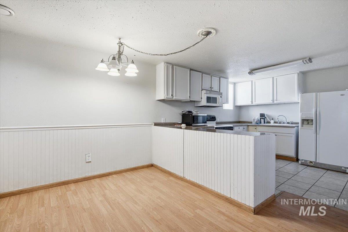 3929-3927 Homestead Road Homedale, ID 83628 - Photo 28 of 45 Kitchen with white cabinetry, stainless steel microwave, and a white refrigerator