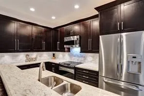 a kitchen with stainless steel appliances granite countertop a refrigerator and a sink