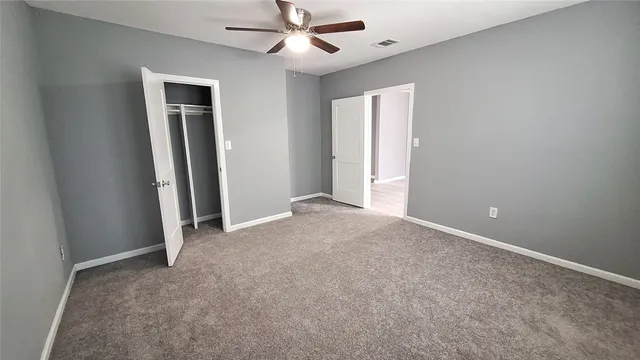 an empty room with closet and a ceiling fan