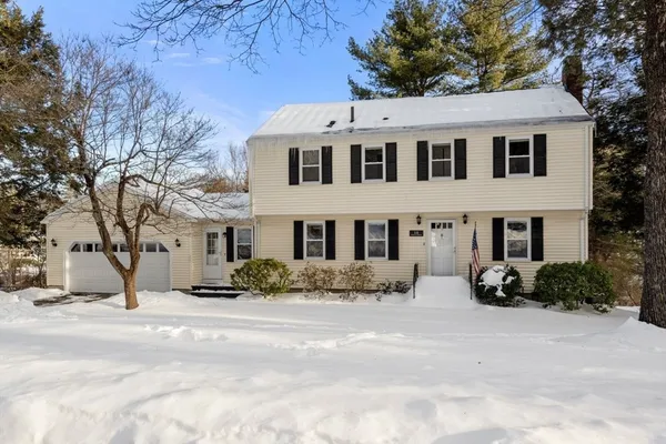 a view of white house with a yard covered with snow
