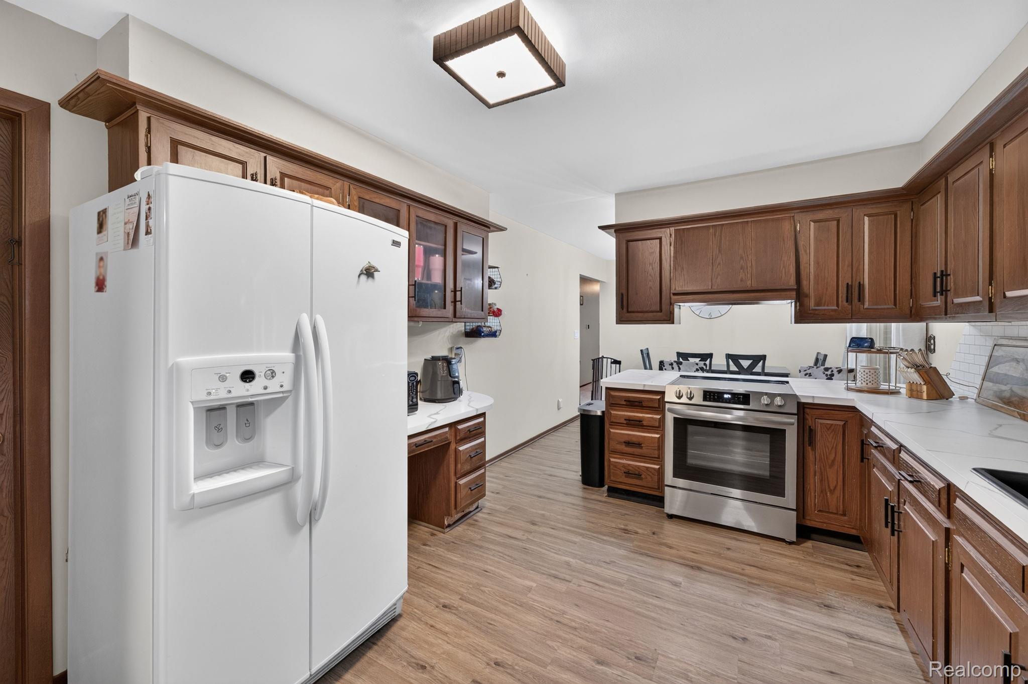 5330 Sheridan Road Saginaw, MI 48601 - Photo 19 of 50 Kitchen featuring wood-finish flooring, white countertops, dark wood cabinetry, and stainless steel appliances