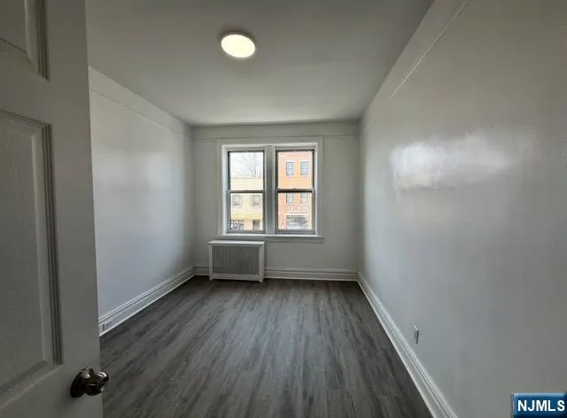 a view of an empty room with wooden floor and closet