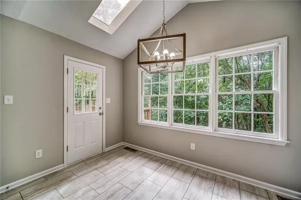 a view of an empty room with a window and chandelier fan
