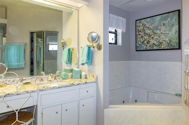 a bathroom with a granite countertop tub a sink and a mirror