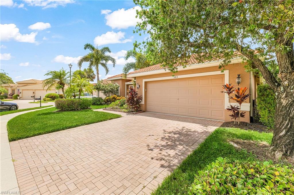 1415 Princess Sabal Point Naples, FL 34119 - Photo 3 of 42 Brick paver driveway leading to a two-car garage, complemented by mature landscaping and a well-maintained lawn