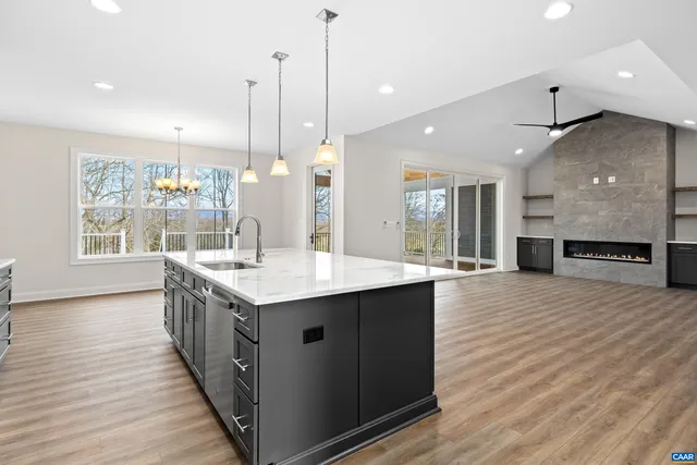 a kitchen with stainless steel appliances granite countertop a refrigerator a sink a stove and a wooden floors