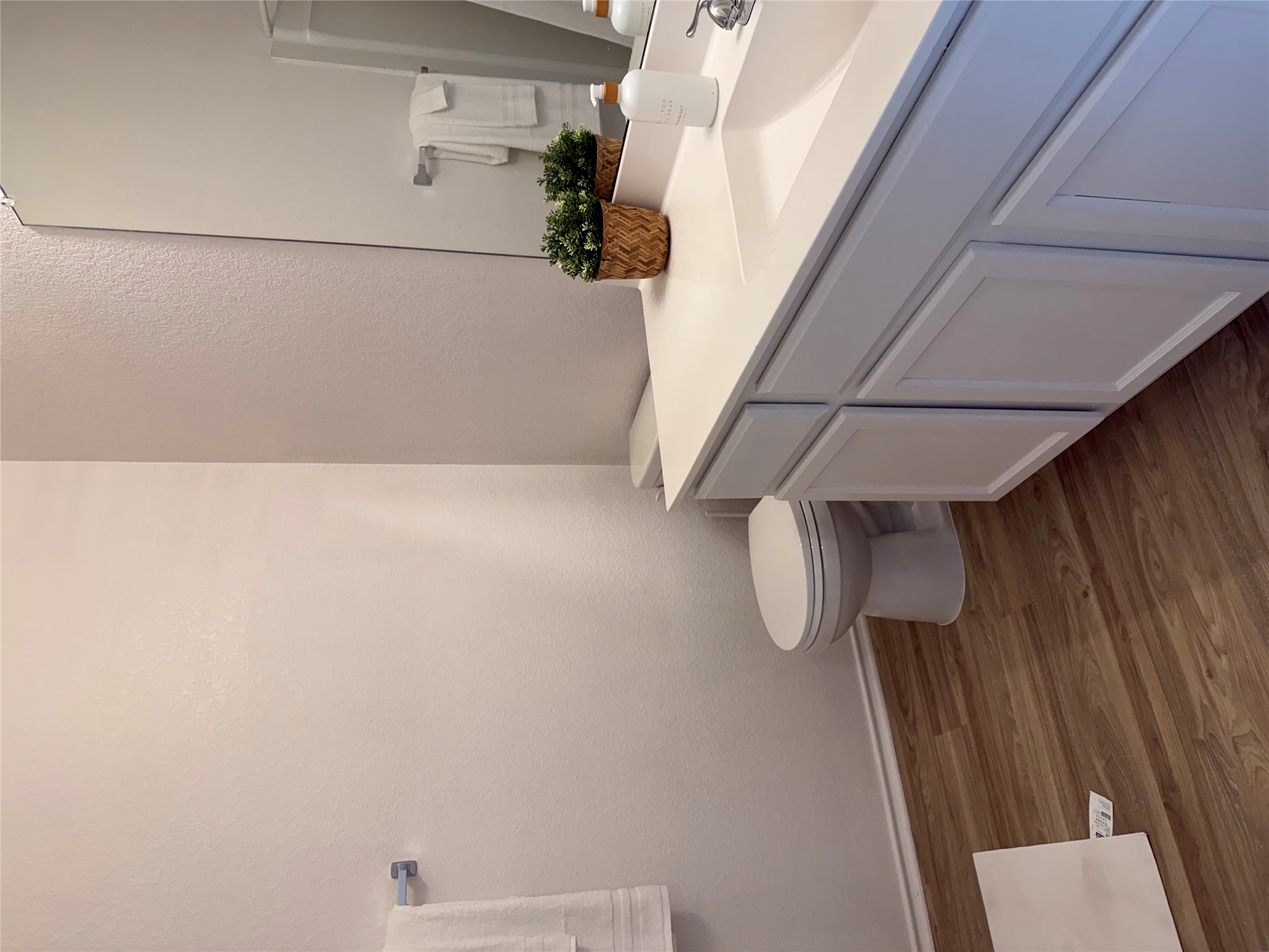 14907 Retha Pass Austin, TX 78725 - Photo 11 of 14 Rich wood-inspired flooring pairs beautifully with the crisp white vanity in this serene bathroom.