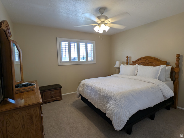 1411 Millbrook Way Bountiful, UT 84010 - Photo 22 of 36 Carpeted bedroom featuring a ceiling fan with light fixture, window with white plantation shutters, and light beige wall paint