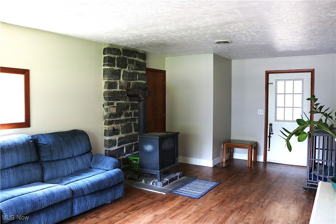 14485 Bass Lake Road Newbury, OH 44065 - Photo 13 of 22 Living area featuring wood finished floors, a wood stove, and a textured ceiling