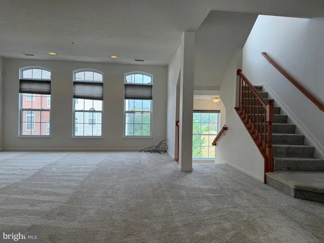 a view of an empty room with stairs and a window