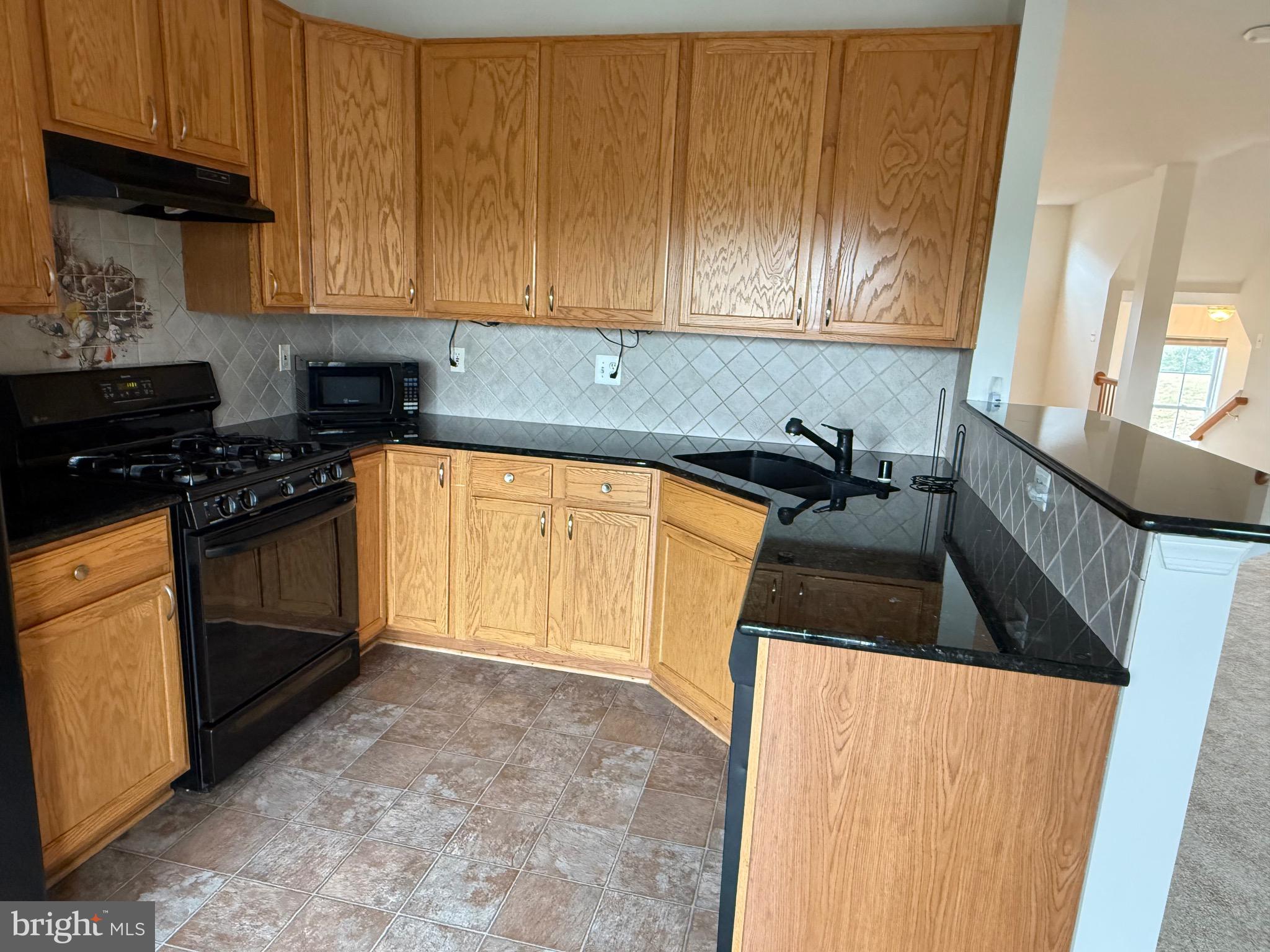 11039 Mill Centre Drive, Unit 11039 Owings Mills, MD 21117 - Photo 10 of 33 a kitchen with granite countertop white cabinets and black appliances