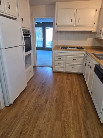 a kitchen with granite countertop wooden floors and white stainless steel appliances