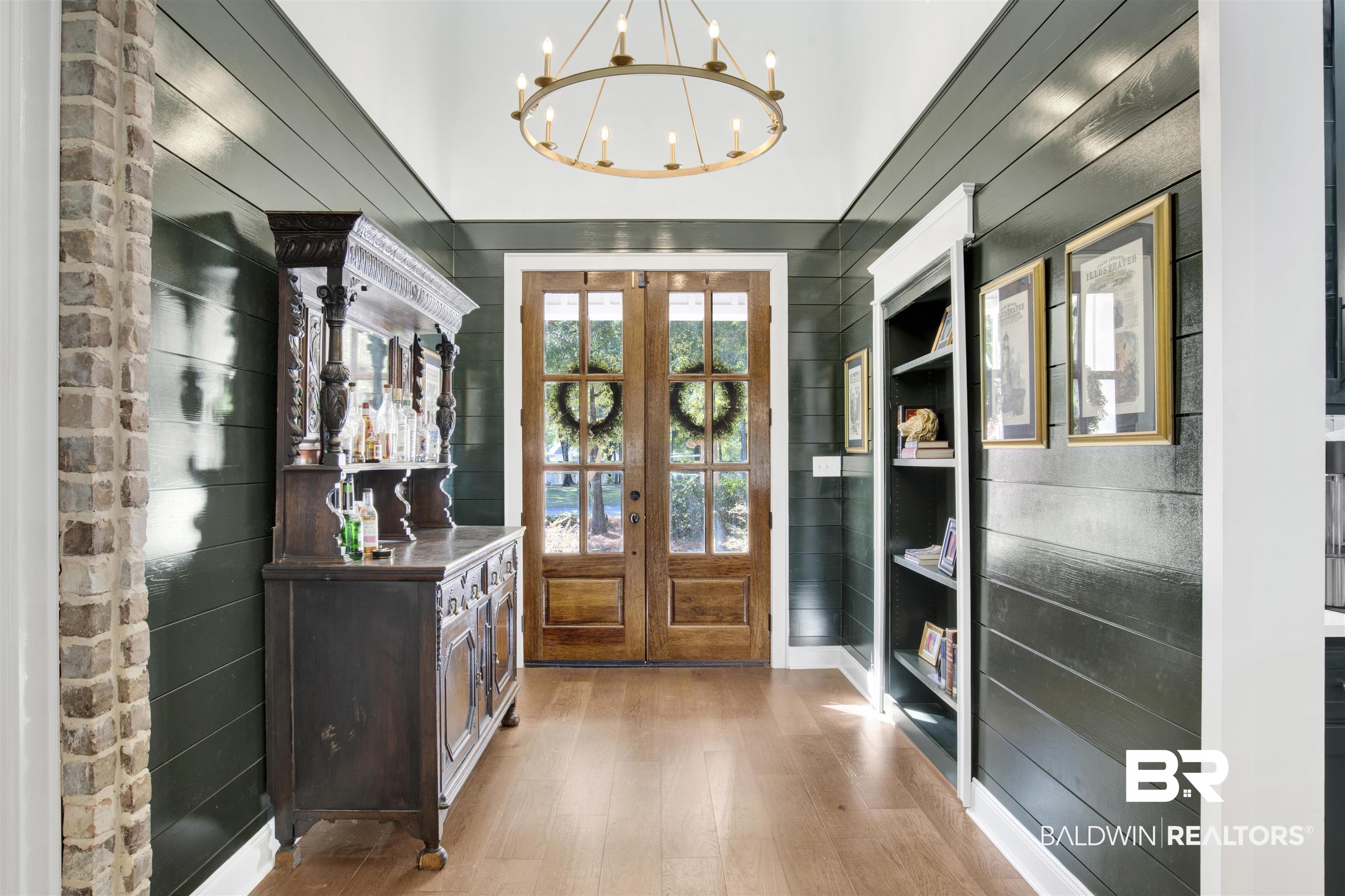 11116 Redfern Road Daphne, AL 36526 - Photo 25 of 46 Entrance foyer featuring wood walls, light wood-style floors, a chandelier, and french doors