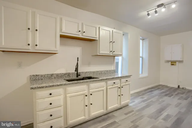 a kitchen with granite countertop white cabinets and a sink