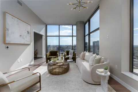 a living room with furniture a large window and a chandelier