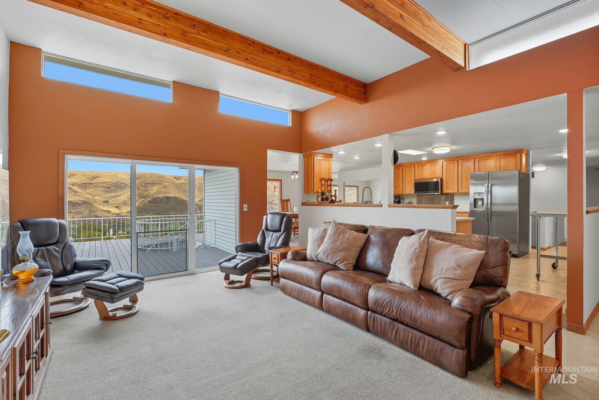 Living area with light carpet, a towering ceiling, a mountain view, and beamed ceiling