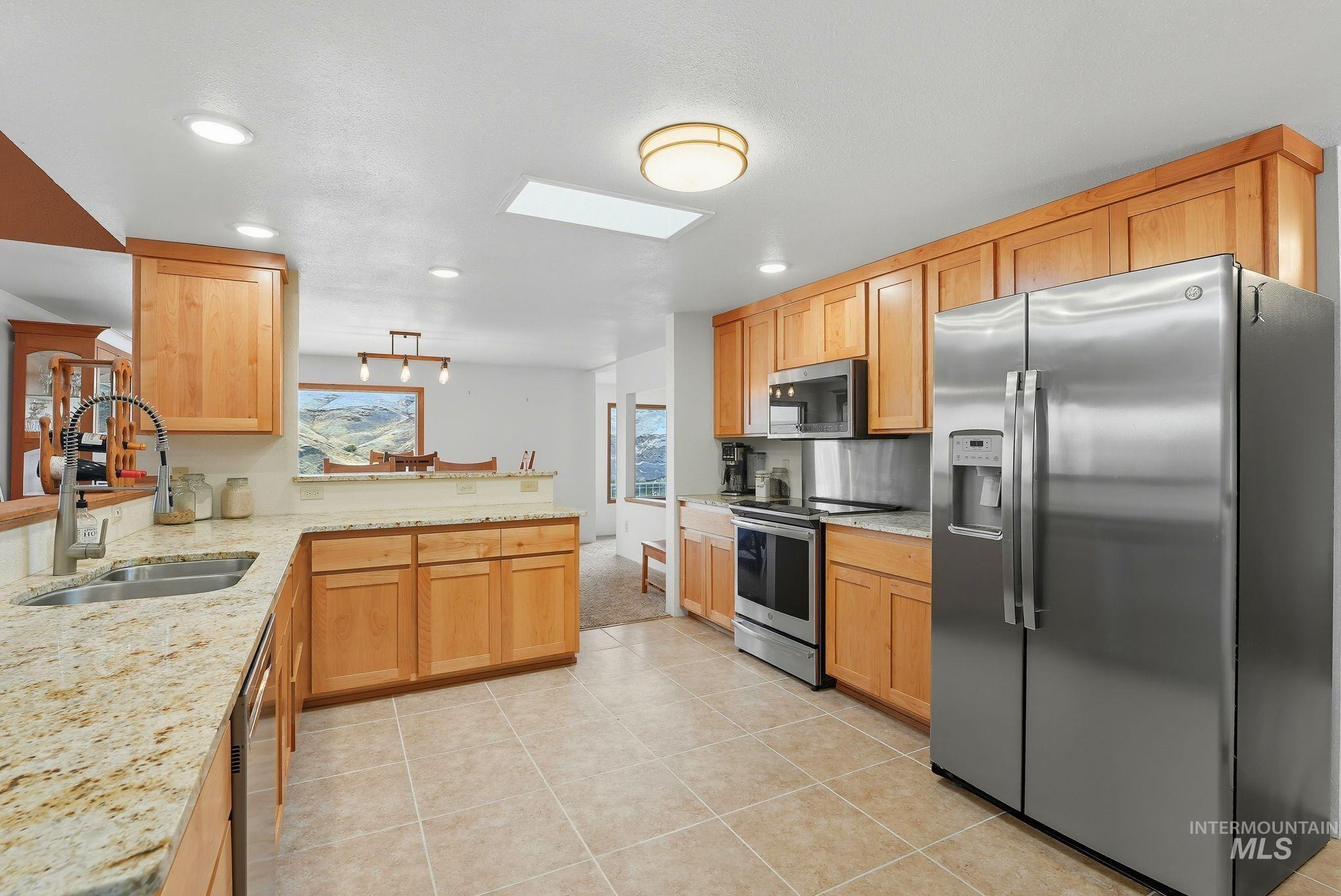 1101 5th Street Asotin, WA 99402 - Photo 15 of 48 Kitchen with appliances with stainless steel finishes, light stone counters, a peninsula, a skylight, and light tile patterned floors