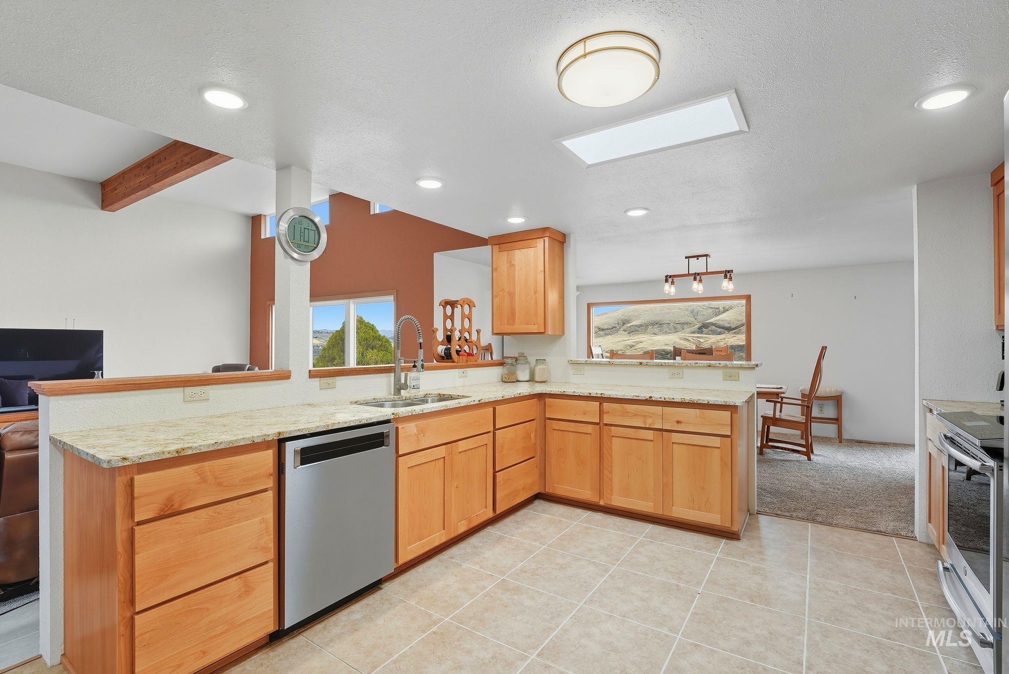 1101 5th Street Asotin, WA 99402 - Photo 17 of 48 Kitchen with a peninsula, stainless steel appliances, light tile patterned flooring, light stone countertops, and recessed lighting