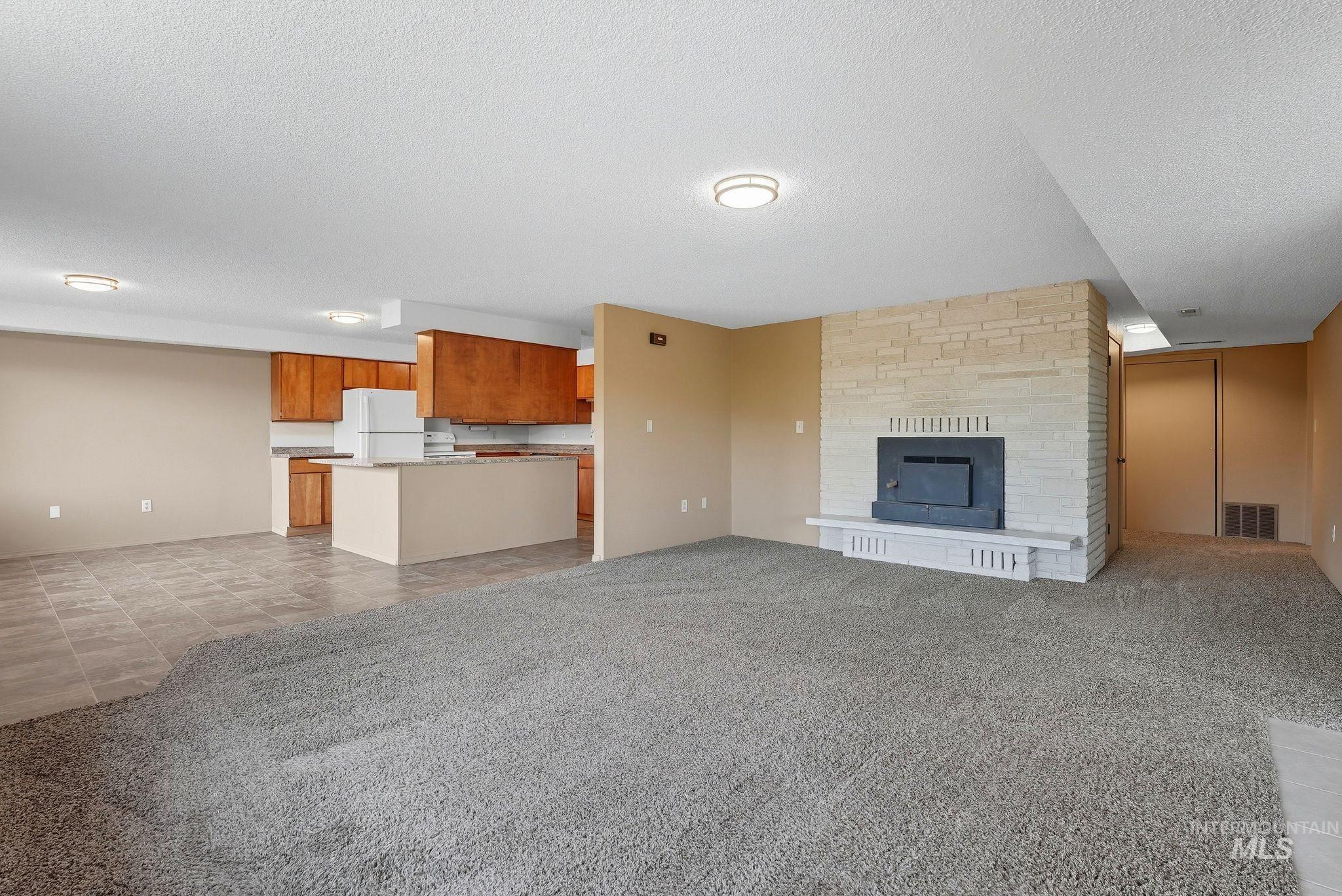 1101 5th Street Asotin, WA 99402 - Photo 32 of 48 Unfurnished living room featuring light carpet, a fireplace, a textured ceiling, and light tile patterned floors