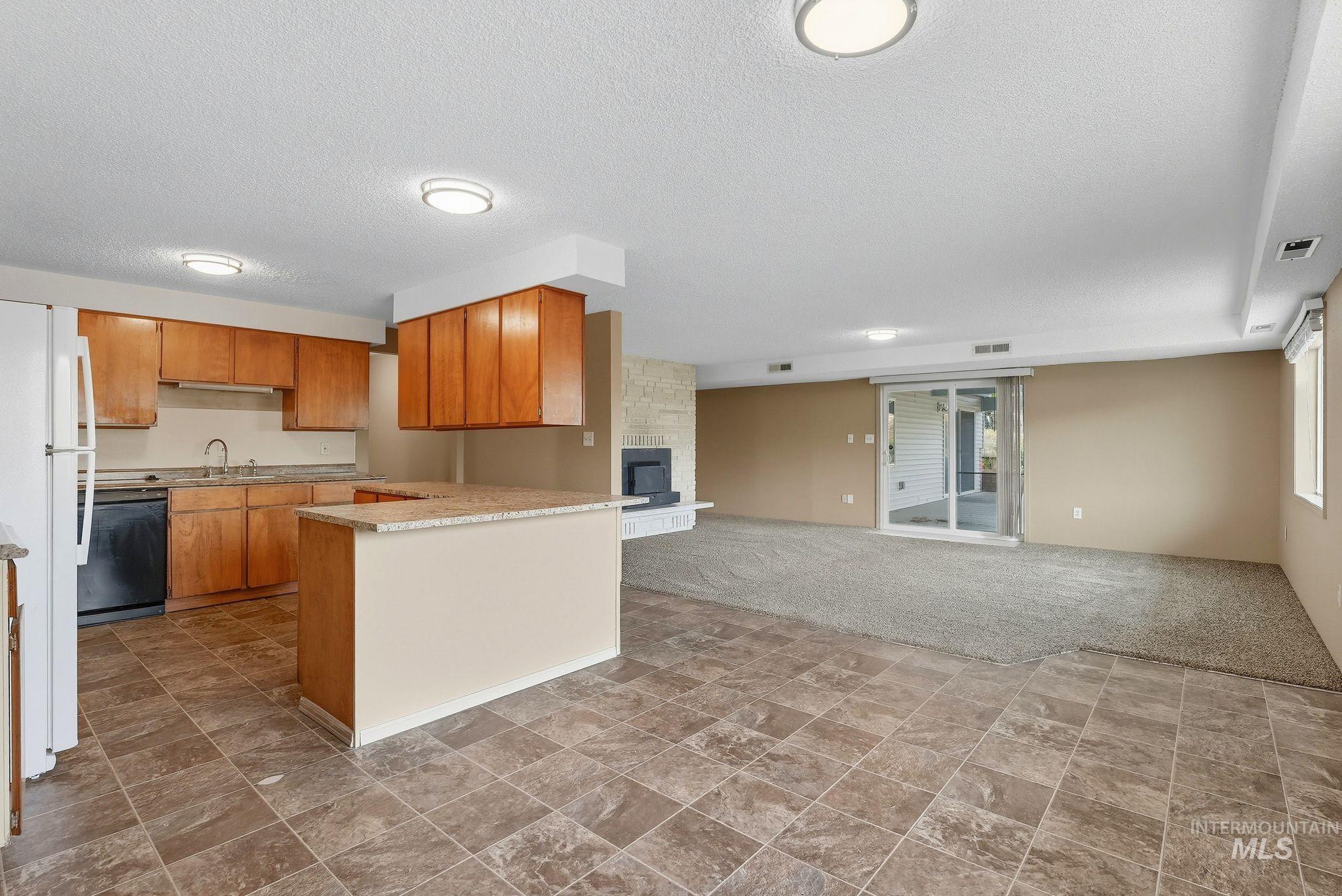 1101 5th Street Asotin, WA 99402 - Photo 48 of 48 Kitchen with freestanding refrigerator, open floor plan, light countertops, a textured ceiling, and brown cabinetry