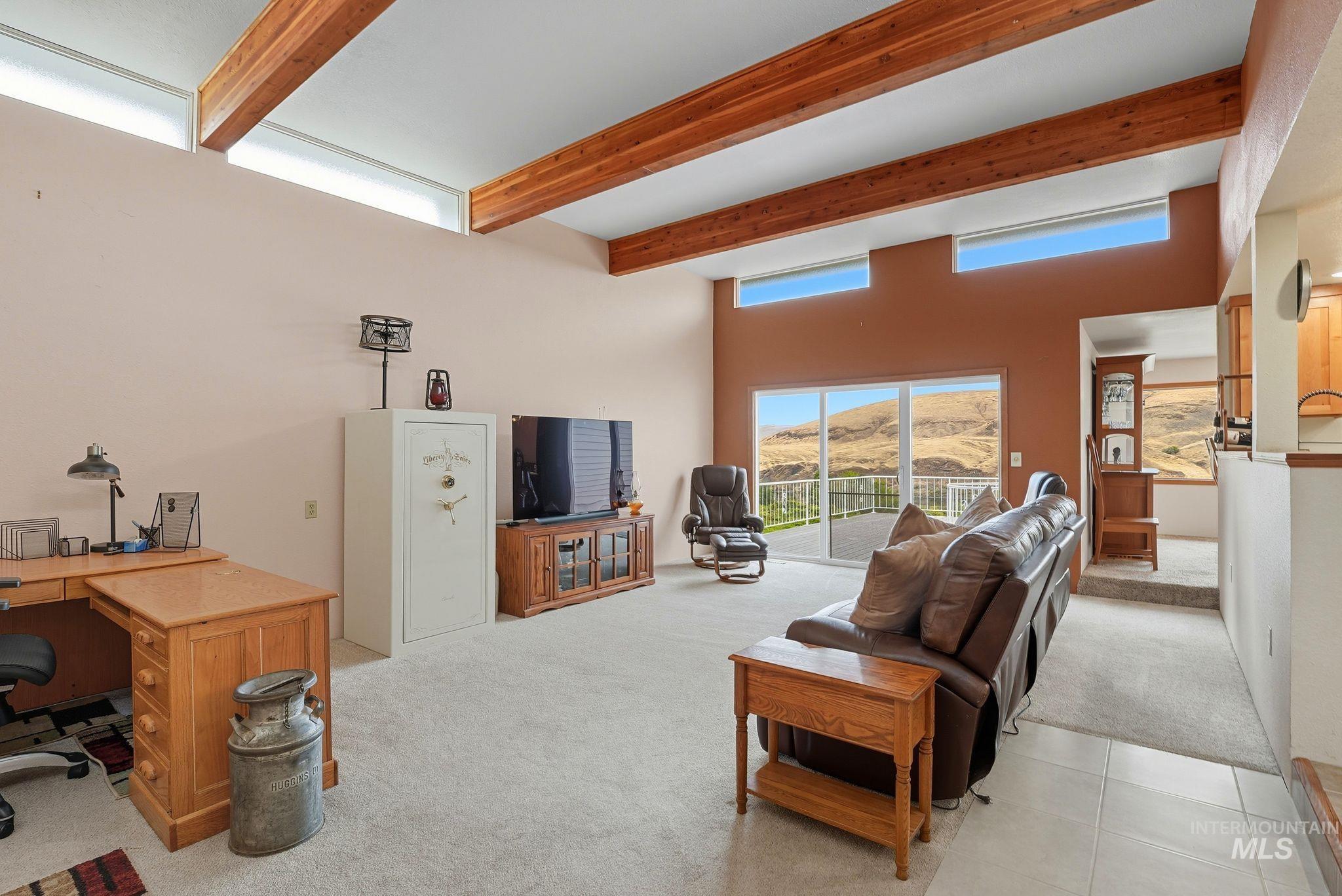 1101 5th Street Asotin, WA 99402 - Photo 9 of 48 Living room with light colored carpet, an office area, beam ceiling, light tile patterned floors, and a high ceiling