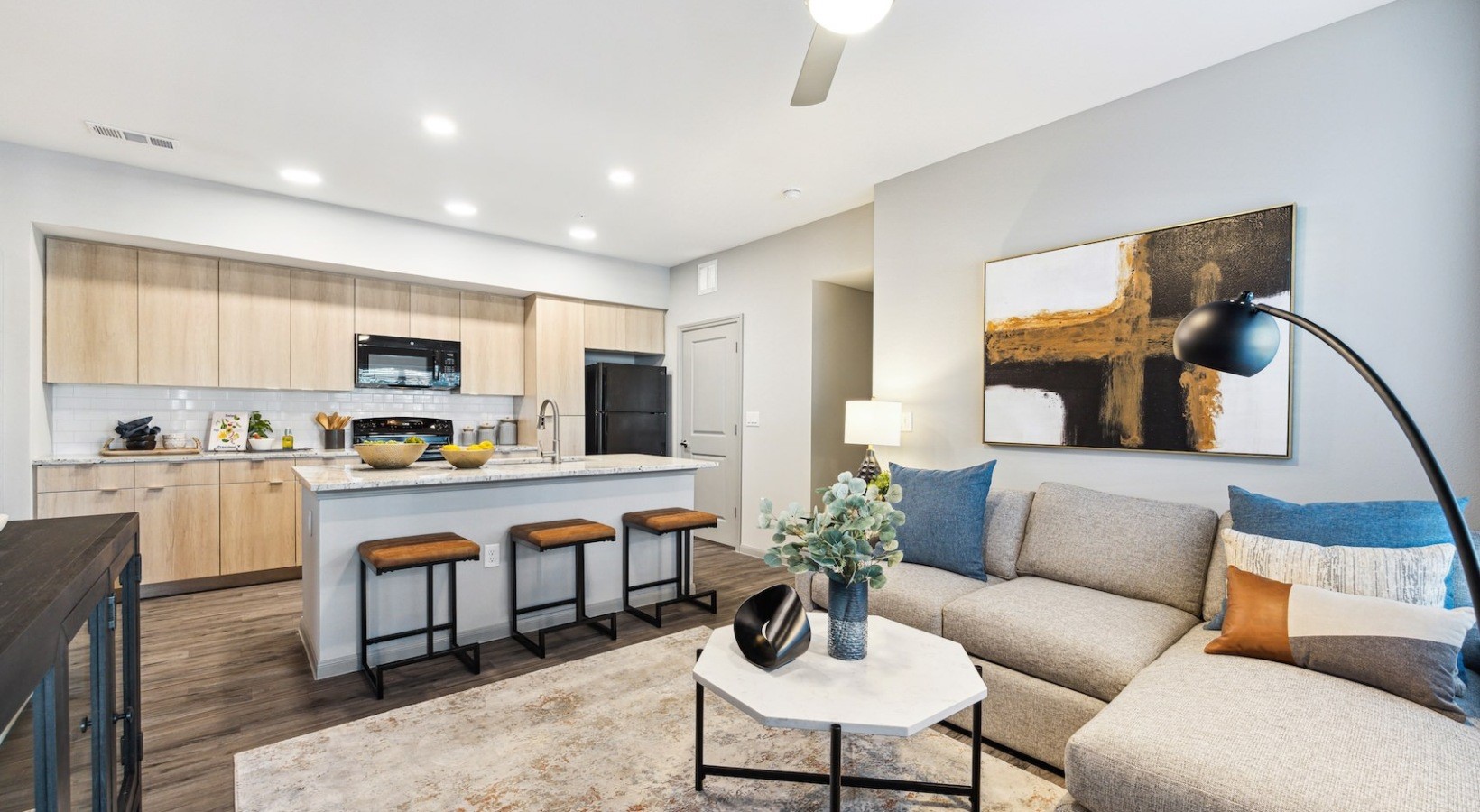 a living room with stainless steel appliances furniture and a kitchen view