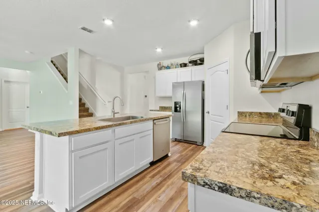 a kitchen with a sink a counter top space stainless steel appliances and cabinets