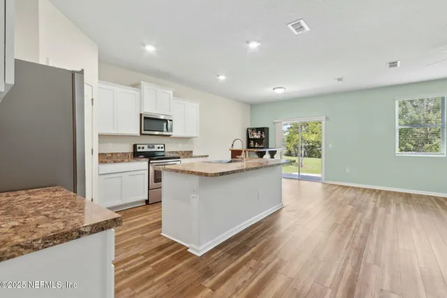 a large kitchen with a center island wooden floor stainless steel appliances and cabinets