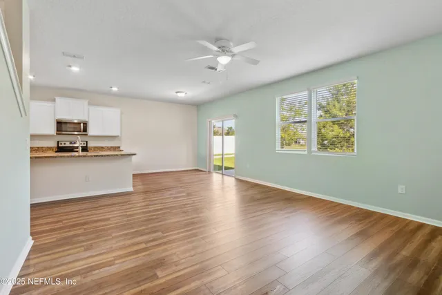 a view of an empty room with a window and wooden floor