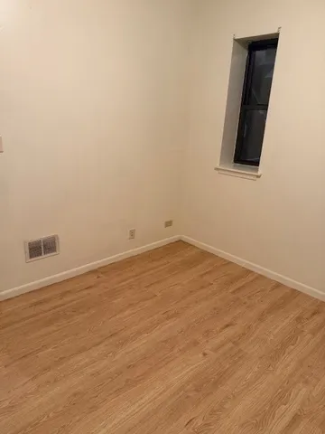 an empty room with wooden floor and a window