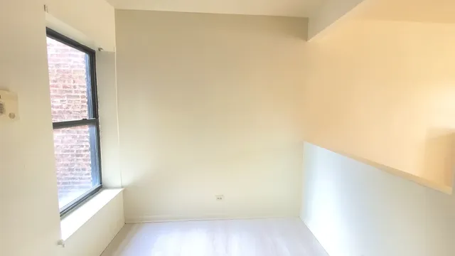 a view of a small space with wooden floor and a window