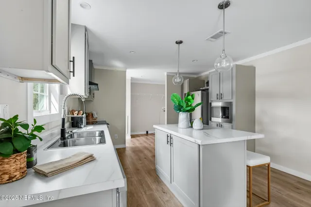 a kitchen with stainless steel appliances a refrigerator a sink cabinets and wooden floor