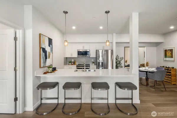 a kitchen with stainless steel appliances kitchen island granite countertop a dining table chairs and white cabinets