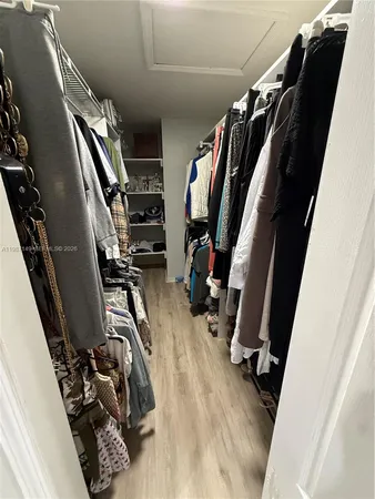a view of walk in closet with clothes and shoes