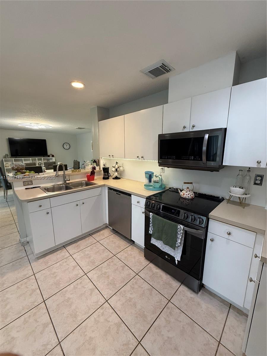 18164 Southwest 149th Place Miami, FL 33187 - Photo 8 of 30 a kitchen with a sink a stove a microwave and cabinets