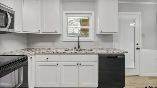 a kitchen with granite countertop white cabinets and sink