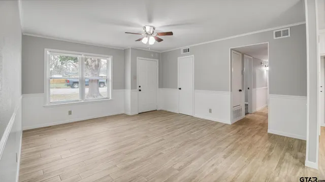 a view of an empty room with wooden floor and a window
