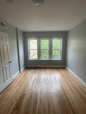 8319 South Drexel Avenue, Unit 3 Chicago, IL 60619 - Photo 2 of 3 an empty room with wooden floor and windows