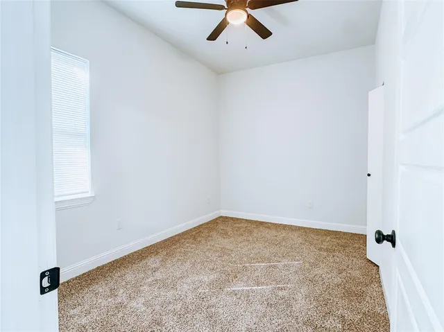 an empty room with a ceiling fan and carpet