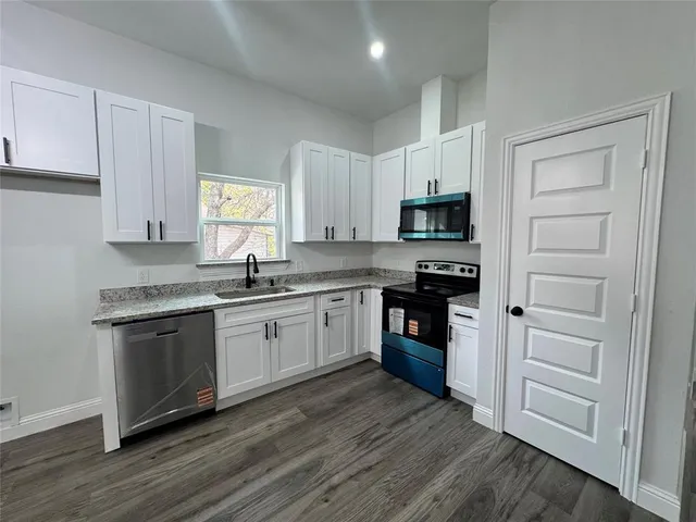 a kitchen with granite countertop a refrigerator stove top oven and sink