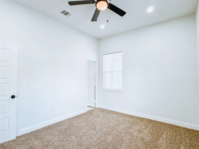 an empty room with a ceiling fan and window