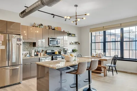 a kitchen with stainless steel appliances kitchen island granite countertop a dining table and chairs