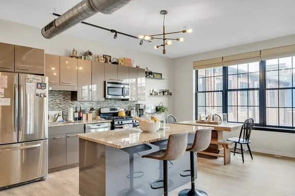 a kitchen with stainless steel appliances kitchen island granite countertop a dining table and chairs