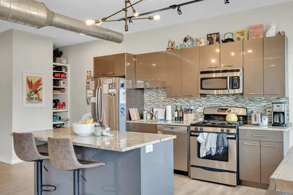 a kitchen with stainless steel appliances kitchen island granite countertop a table chairs in it and wooden floors