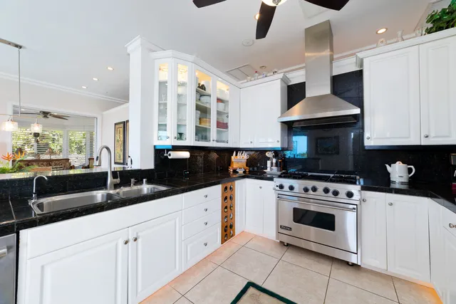 a kitchen with stainless steel appliances granite countertop a stove a sink and white cabinets